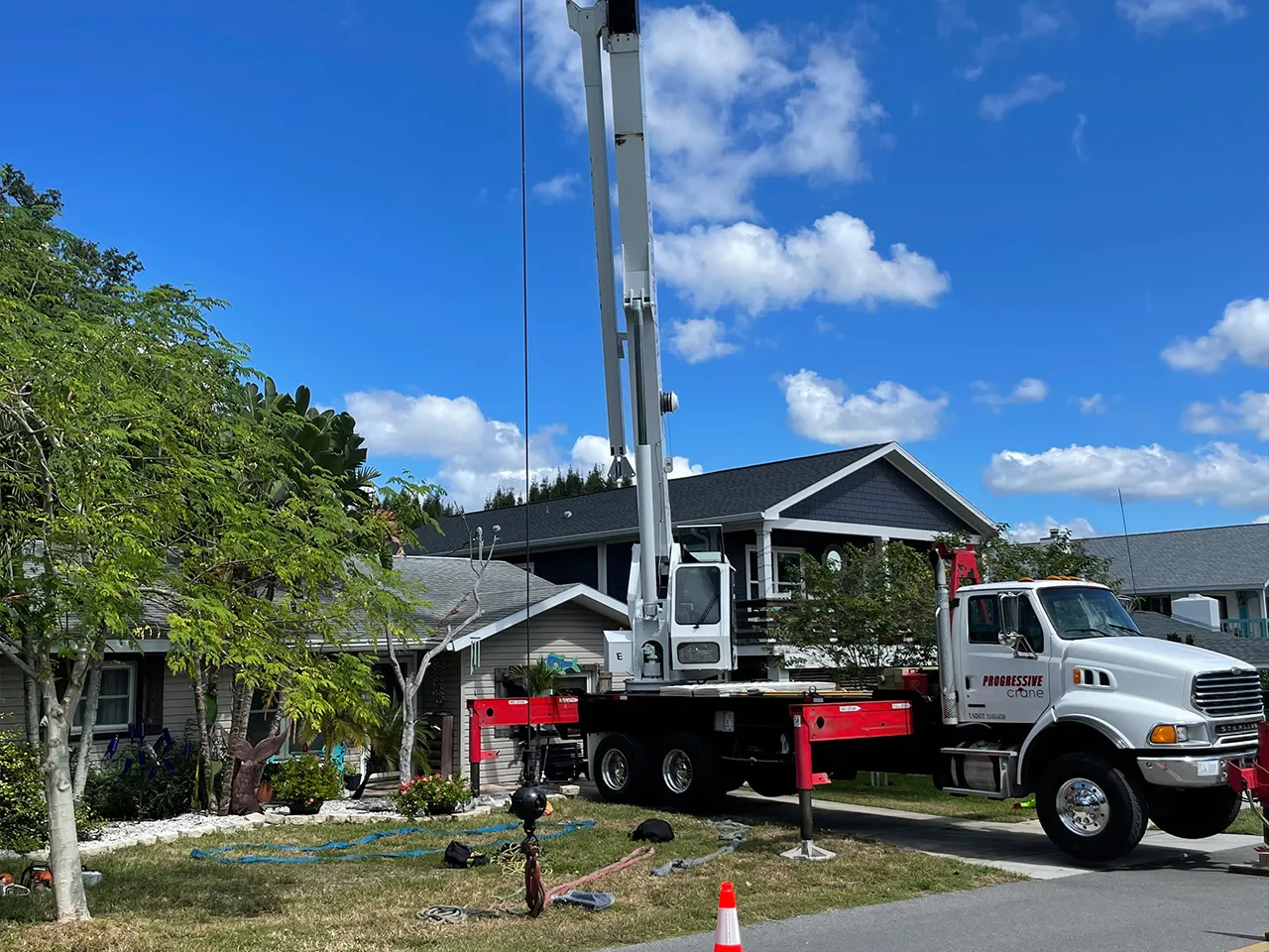 Crane lift removing large tree sections near a home in South Tampa